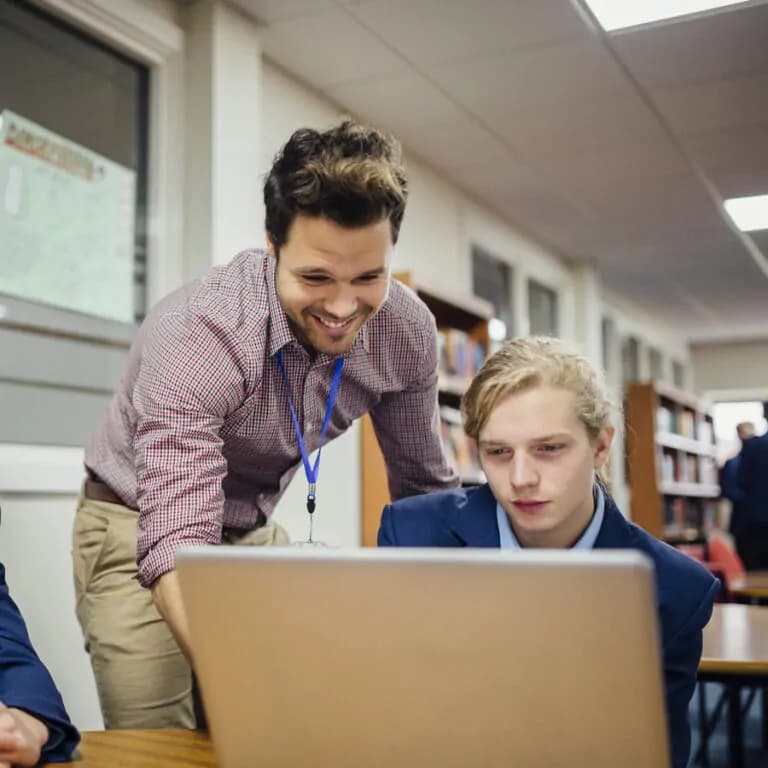 A teacher looking at a laptop screen with a student