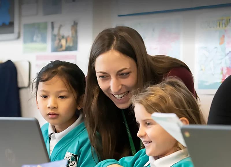 A teacher with two students looking at a laptop screen